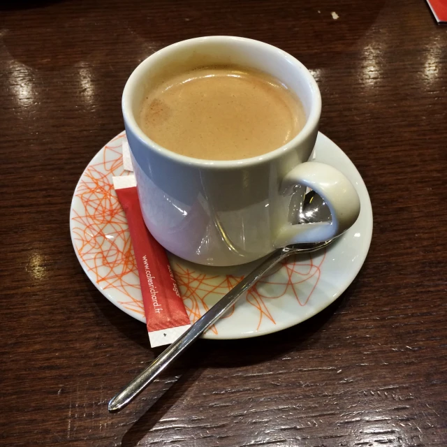 a cup of coffee with spoon and card with candy bar