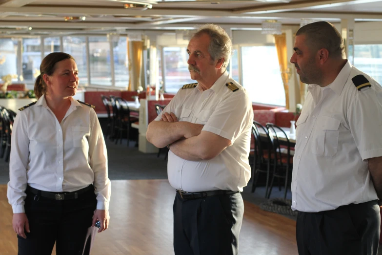 three sailors look at each other and smile in a restaurant
