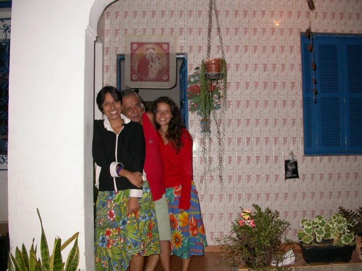 three people posing for the camera in front of a wall