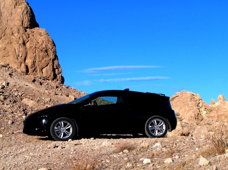 a car parked in front of some rocks and mountain