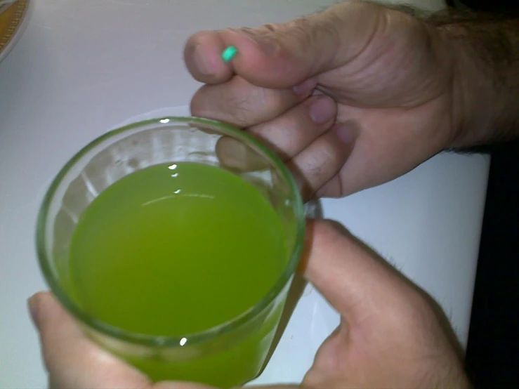 a man holds a green liquid from his left hand