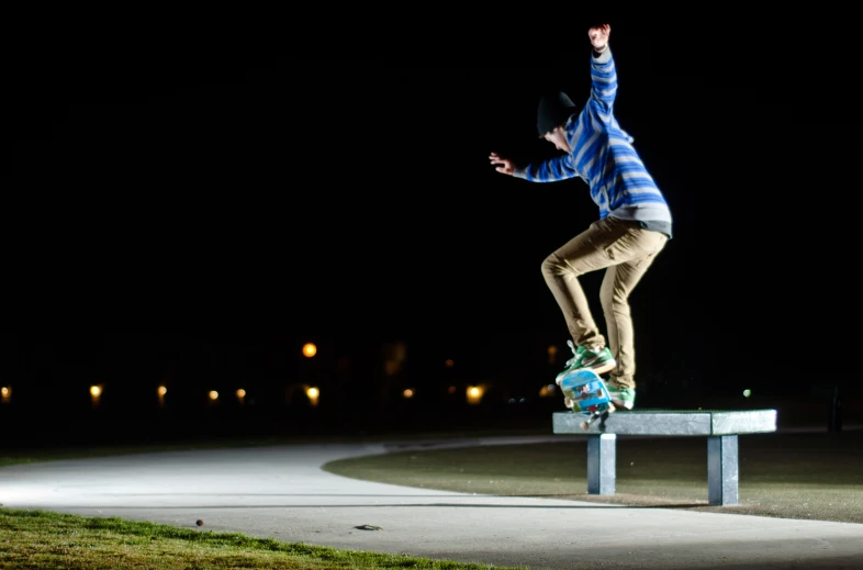 man on a bench doing skateboard tricks at night