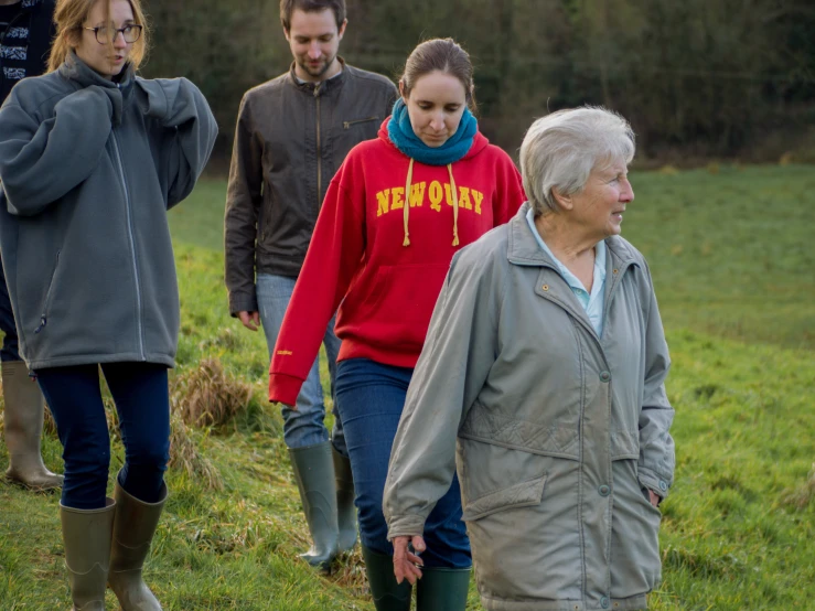 people walking in a field with grass and tall bushes