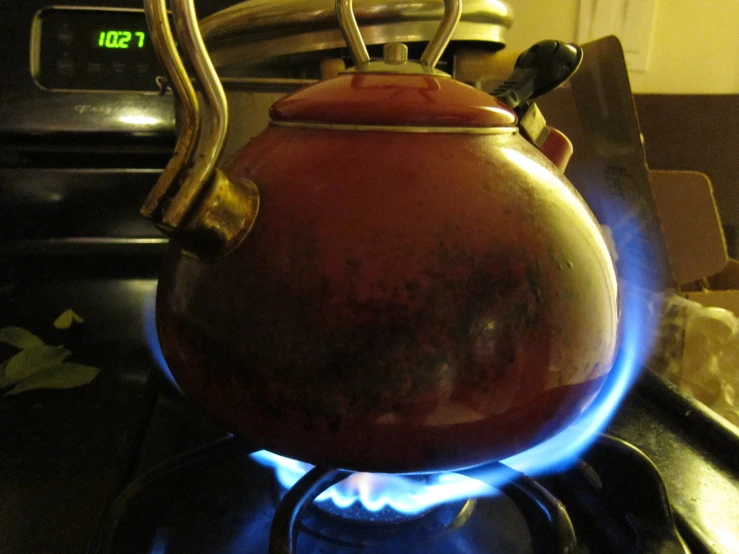 a red tea kettle is sitting on top of a stove