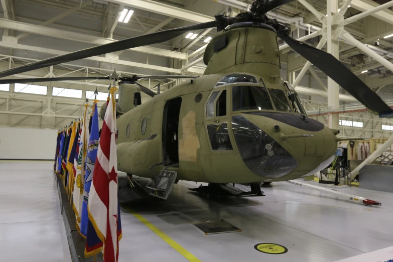 a military helicopter with four propellers and flags