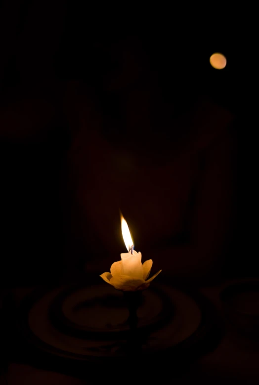 a single candle sitting on a table with a black background