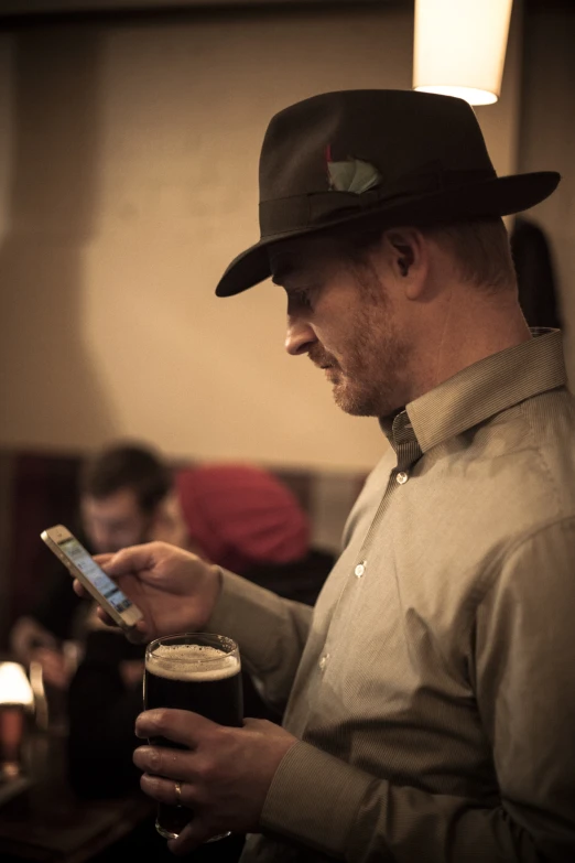 a man is holding a phone in his hand while holding a glass