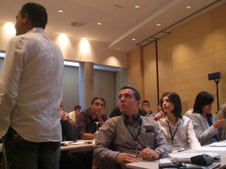 a group of people sitting at tables in a conference room