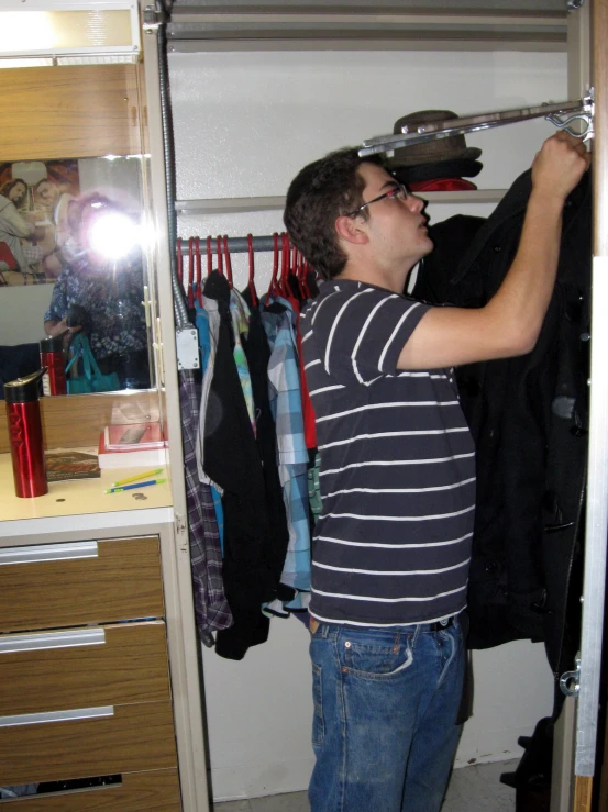 a man holding an object and looking in the closet