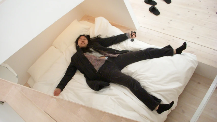 a man in black pants lies on a white bed