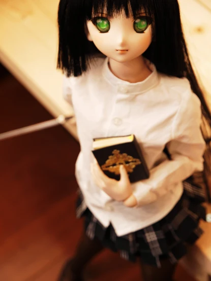 a doll holding a book on a wooden floor