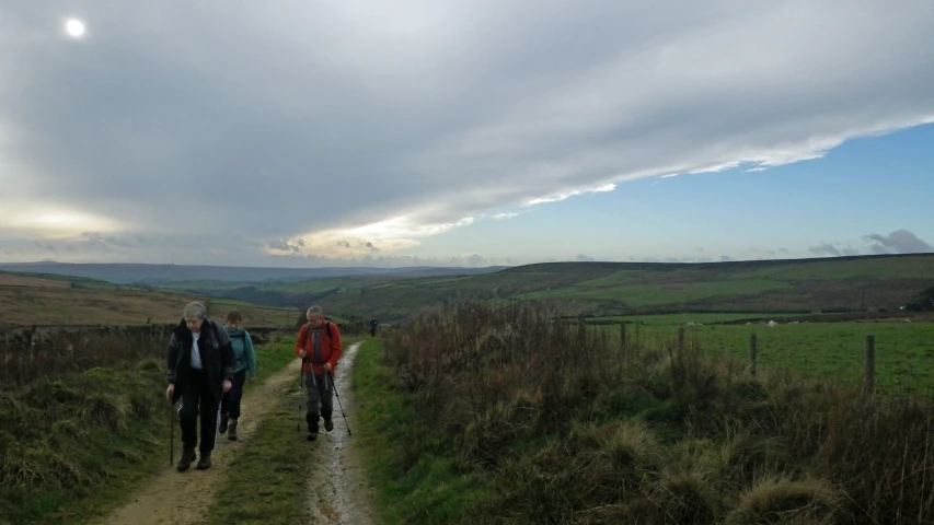 three people hiking up a gravel road together