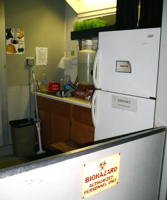 a kitchen with two refrigerators, a sink and a trash can