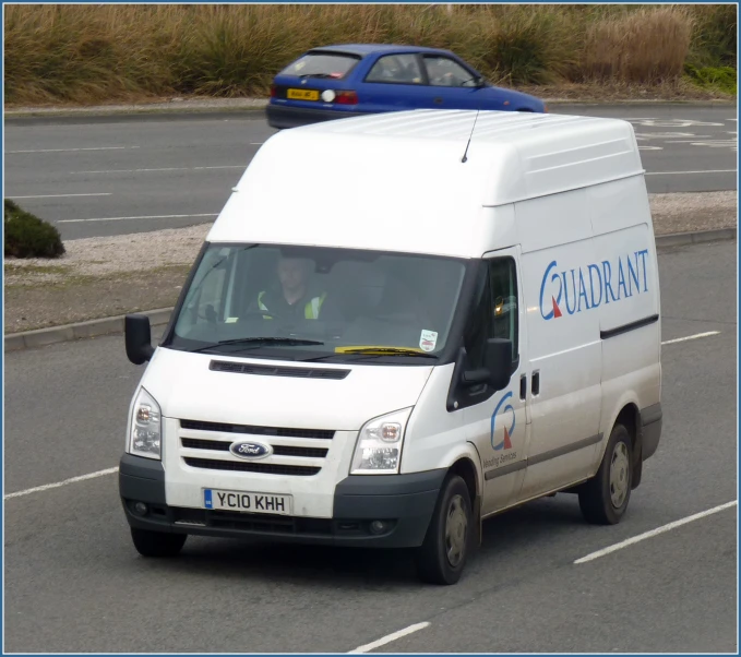 a white van driving down a street next to two blue cars