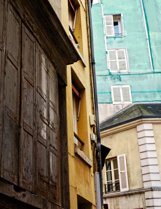 an old yellow building has shutters and windows on it
