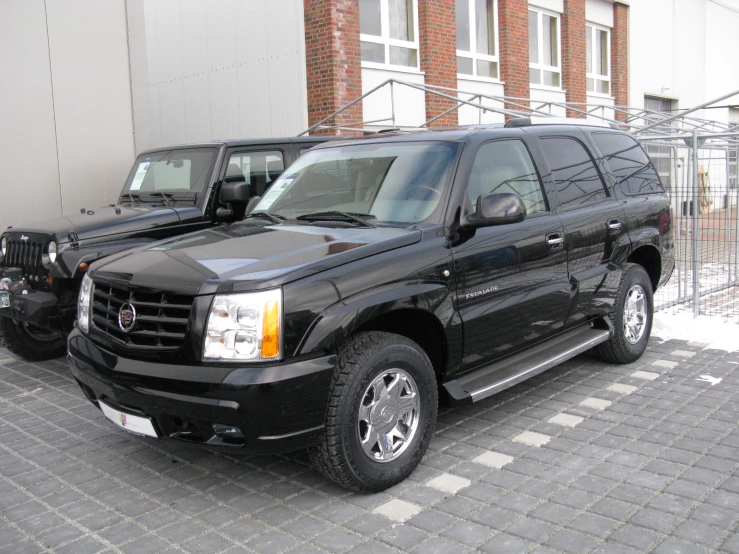 two black trucks parked on a paved sidewalk