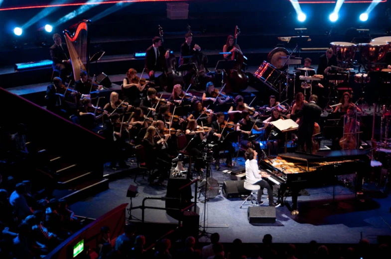 a man is standing at a piano with many musical instruments on stage