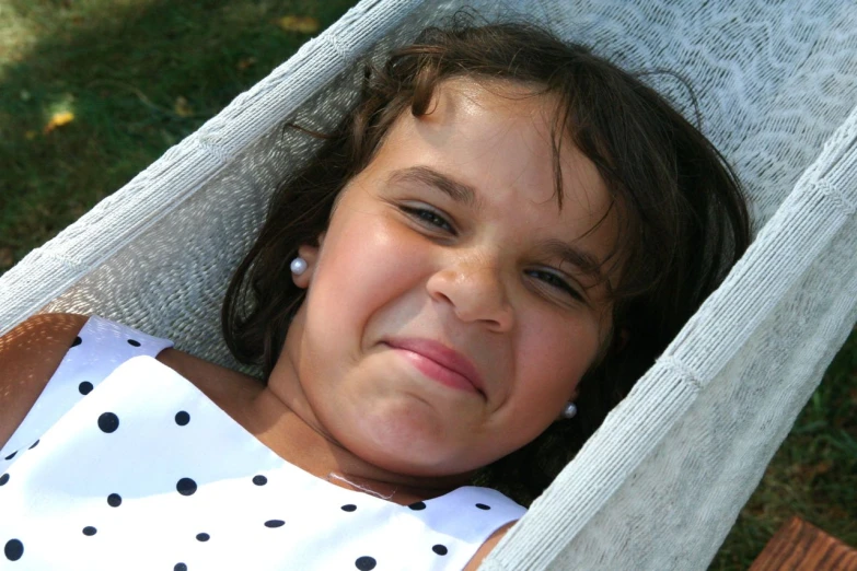 a little girl laying in a hammock with her eyes closed