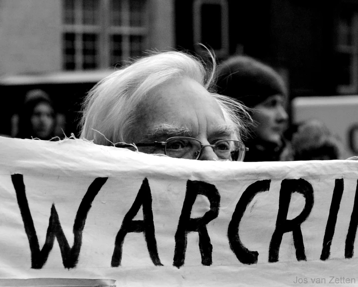 an old man holding up a sign that says warcraft