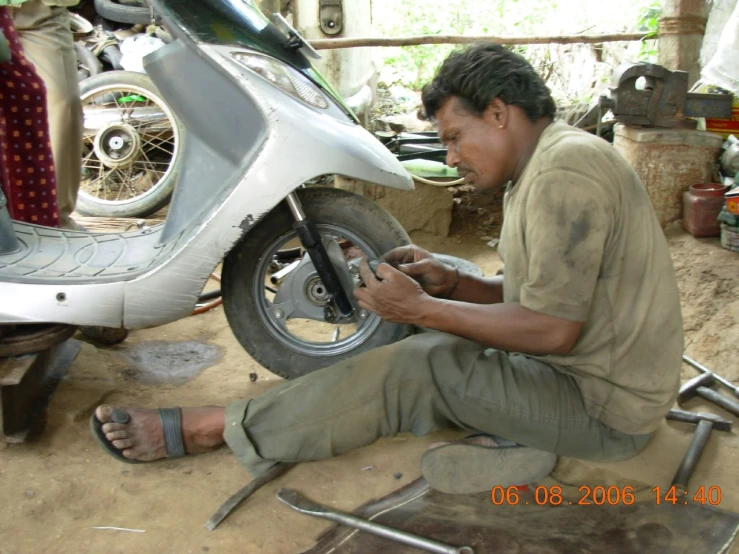 a man sitting on a floor working on the rim of a motorbike