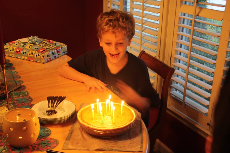  in black shirt blowing out the candles on his birthday cake