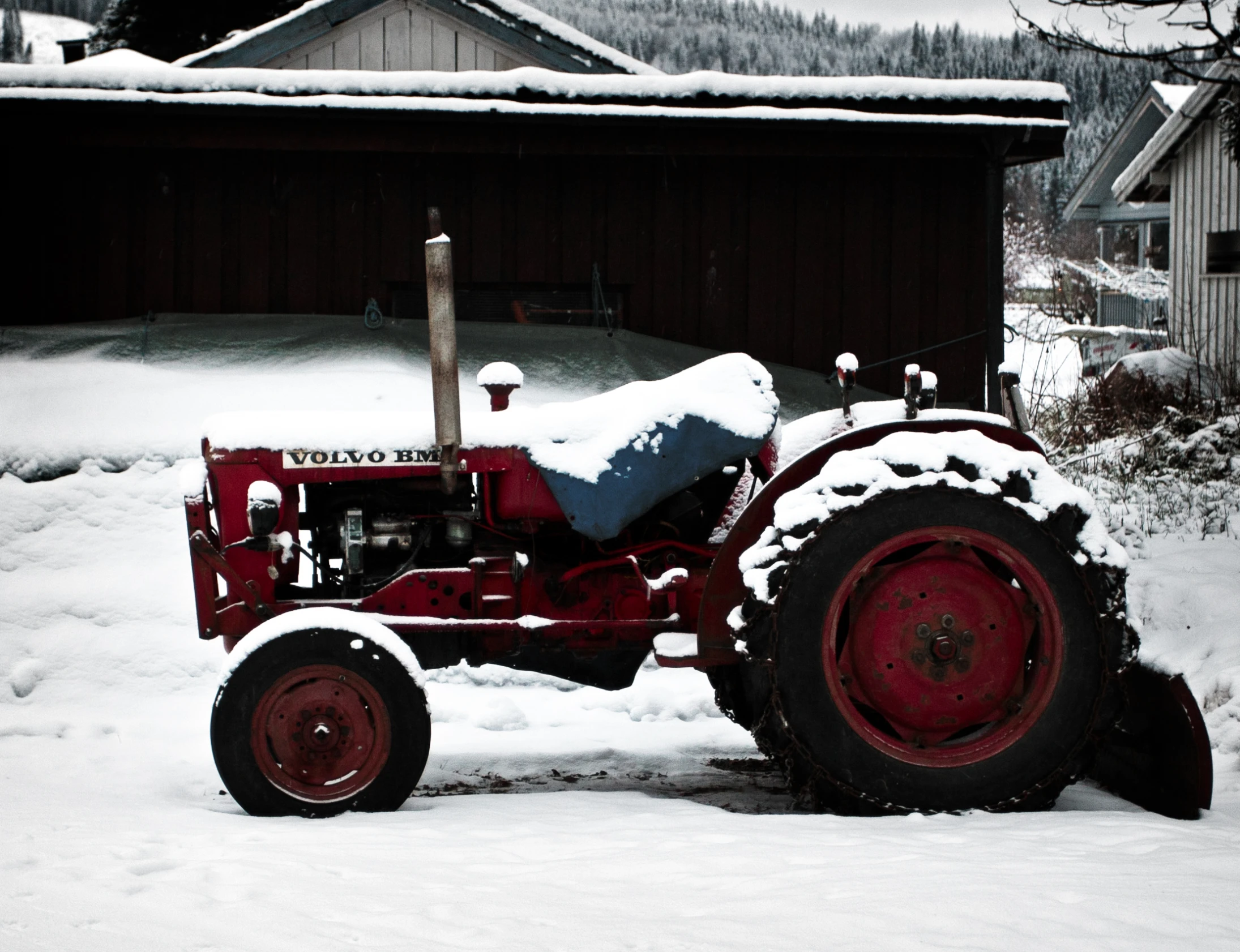 a tractor is covered with snow outside the barn