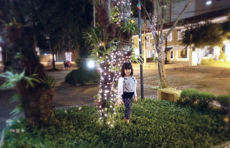 small child standing in front of a street light with lights strung up all over