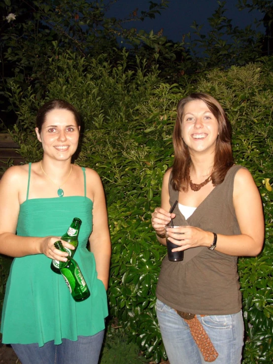 two people that are standing together holding beers