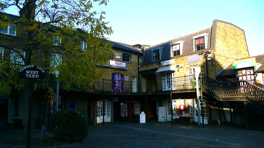 an old city alley with a tree, stairs and storefront