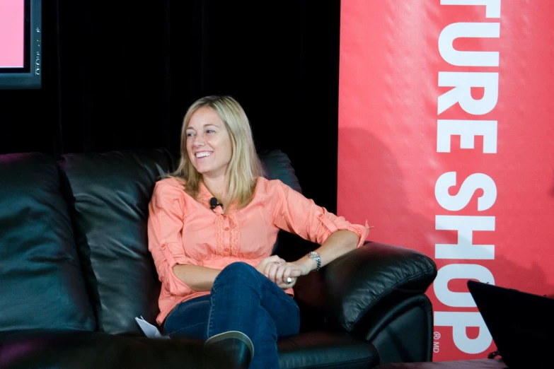 a woman smiles and sits in a black chair