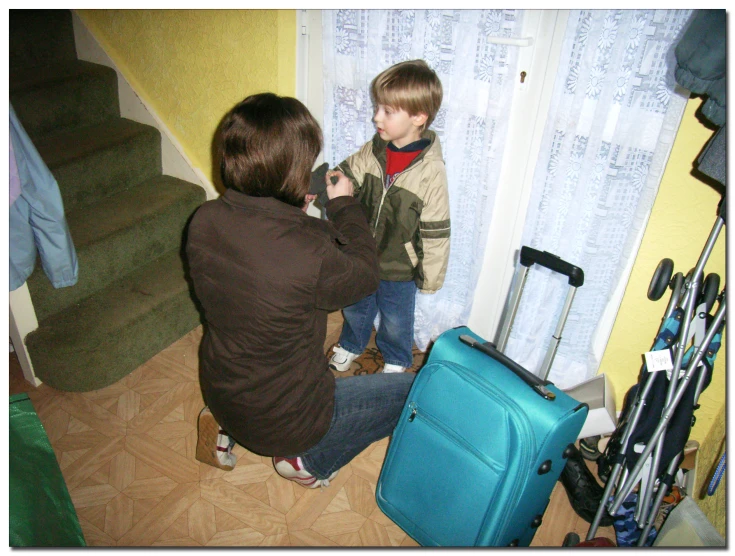 two s playing with their luggage by a window