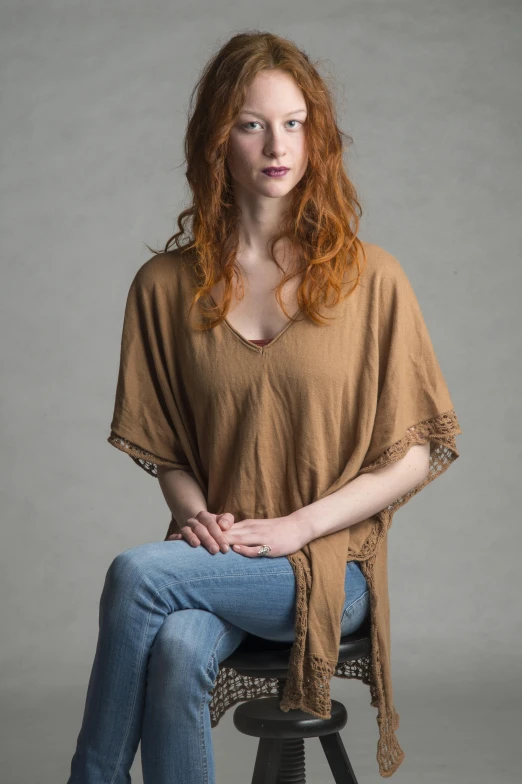 a young woman with red hair sitting on top of a stool