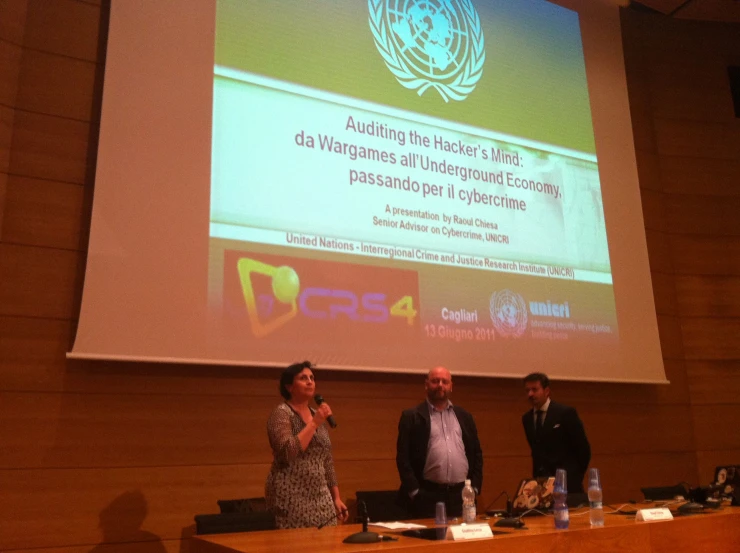 two men and a woman standing in front of a big screen