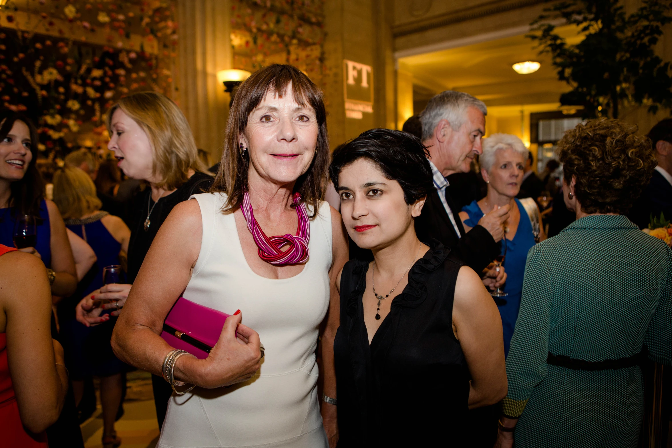 two women pose for a pograph at a party