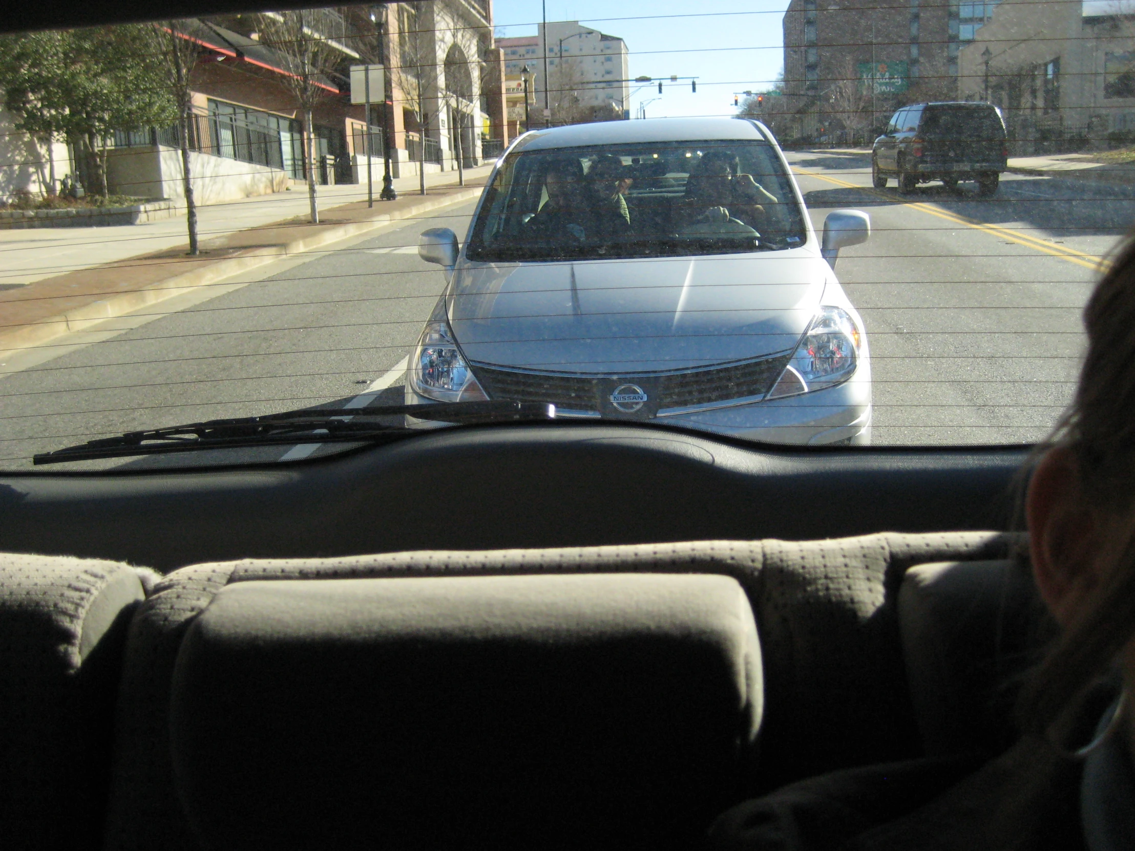 the white car is traveling on the busy city street