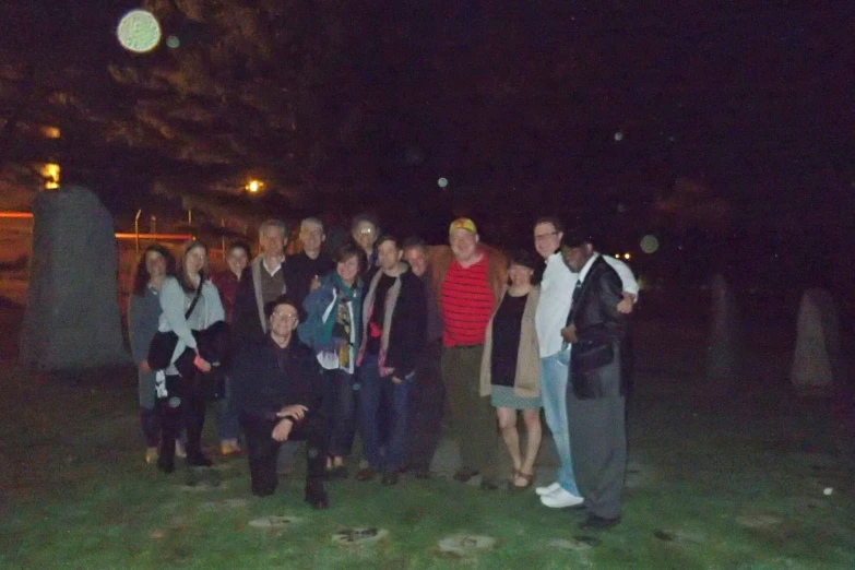 people standing together in a grassy area at night