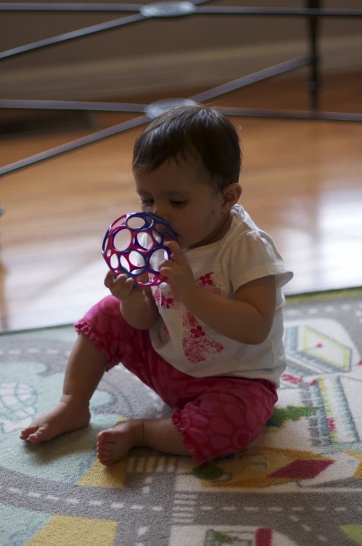 a baby sits on the floor playing with a large ball