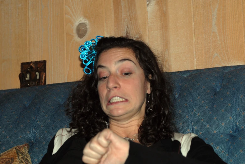 a woman with black hair sitting on a blue couch