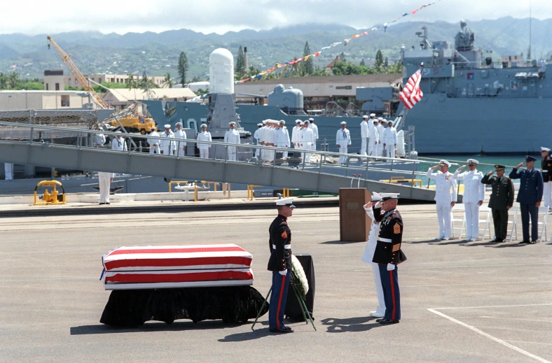 several sailors in uniform standing beside a casket