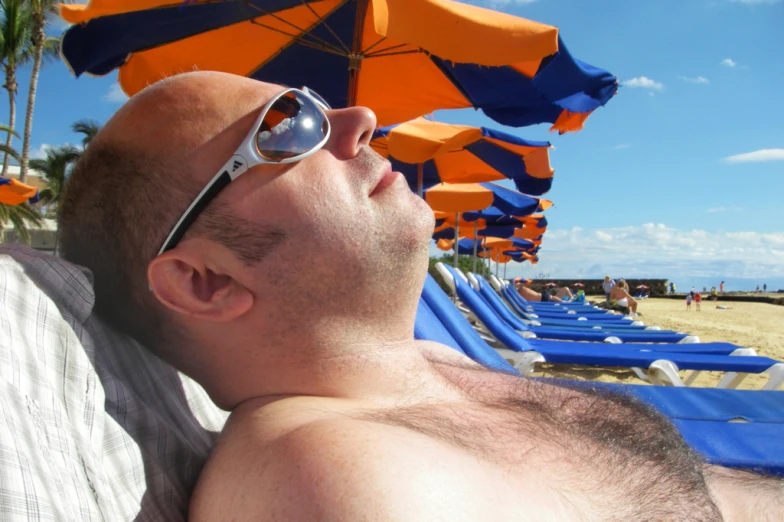 a man laying on a beach with sun glasses