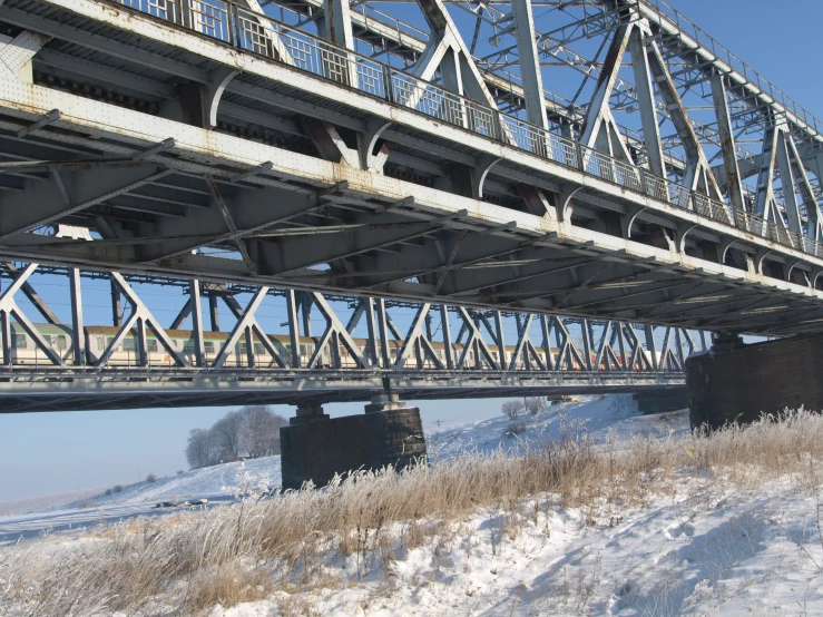 the train bridge is high above the snowy fields