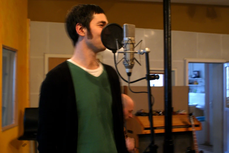 a man holding a guitar and standing in front of a microphone