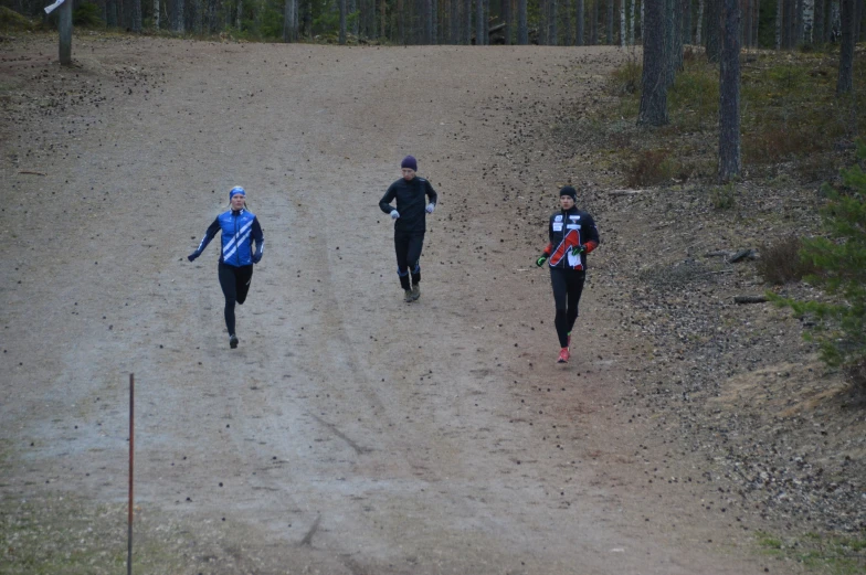three people wearing different hats and running down a dirt road