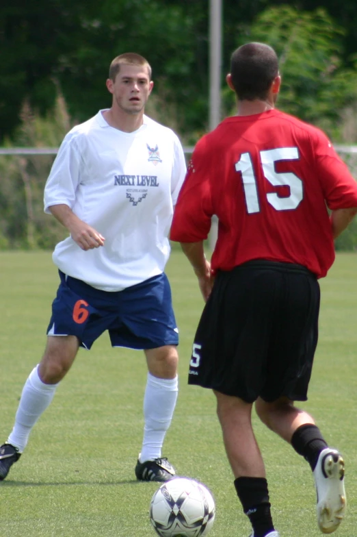 two men on soccer field about to kick the ball