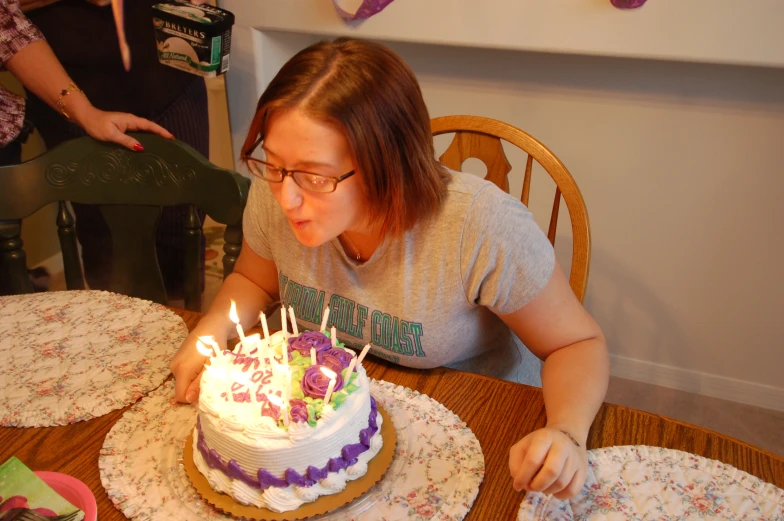 a woman blowing out candles on a birthday cake