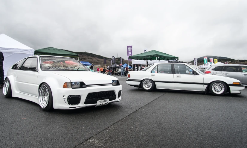 two white cars are parked near one another