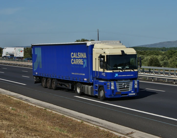 a blue and white truck is going down a freeway