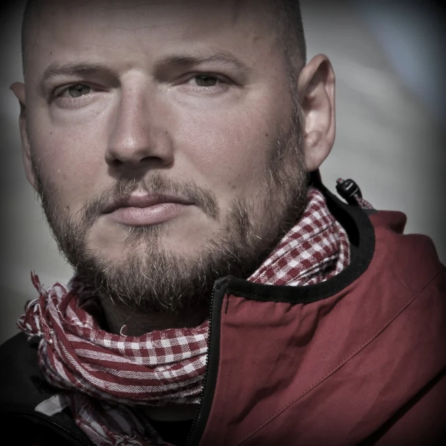 a man with a scarf around his neck stares at the camera