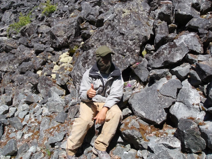 a man sitting on some rocks talking on his cell phone