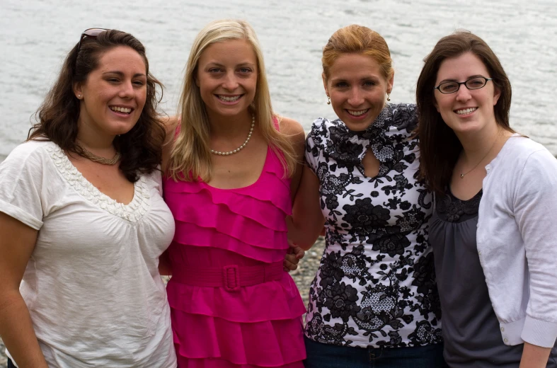 four women pose for the camera with the water in the background